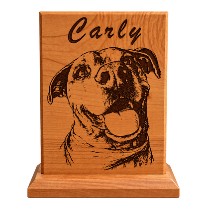 A personalized wooden plaque featuring a engraved portrait of a dog and the name 'Carly' at the top, displayed on a wooden stand on a desk.